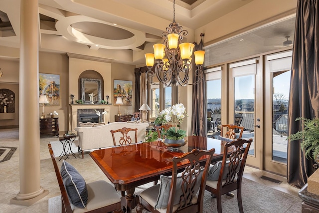 dining space featuring an inviting chandelier, light tile patterned floors, a premium fireplace, and ornate columns