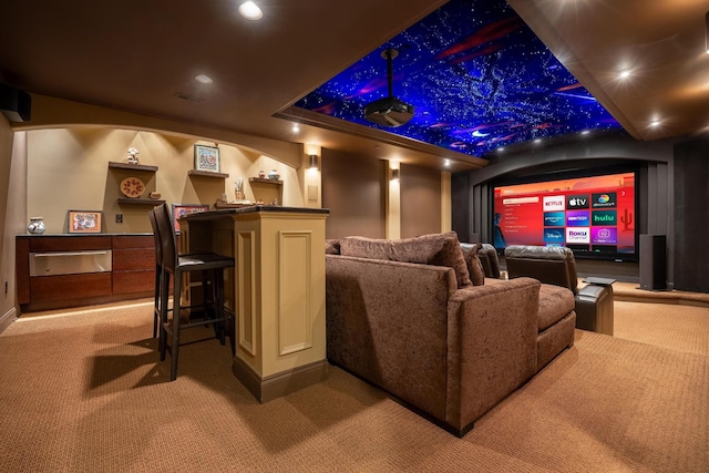 carpeted cinema room with bar area and a raised ceiling