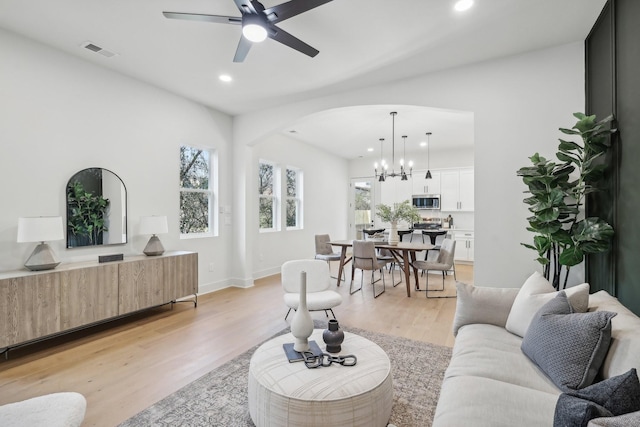 living room featuring ceiling fan with notable chandelier and light hardwood / wood-style floors