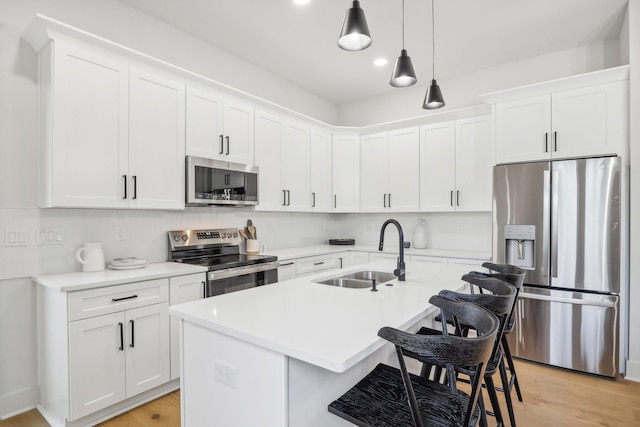 kitchen with appliances with stainless steel finishes, sink, hanging light fixtures, and white cabinets