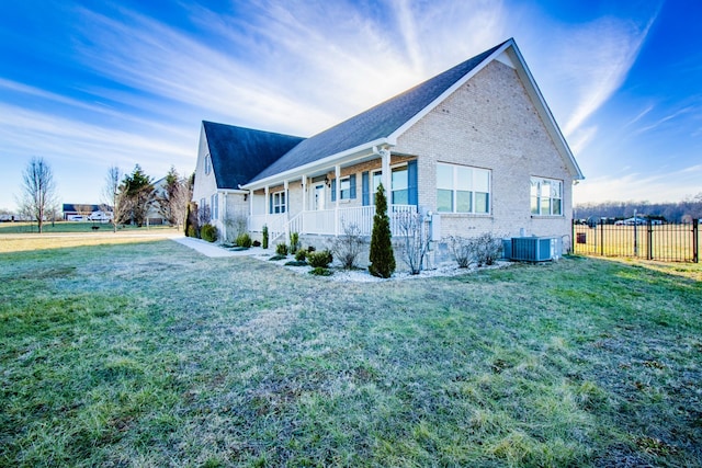 view of property exterior with a porch, central AC unit, and a lawn