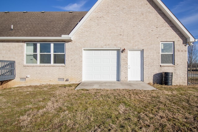 back of property featuring a garage and a lawn