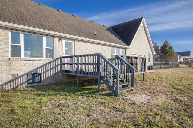 back of property with a deck and a lawn