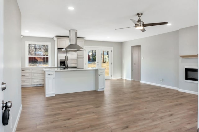 kitchen featuring a center island, plenty of natural light, stainless steel fridge, light hardwood / wood-style floors, and white cabinets