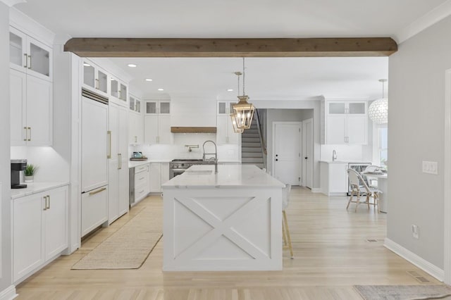 kitchen with an island with sink, white cabinetry, hanging light fixtures, custom exhaust hood, and light stone counters