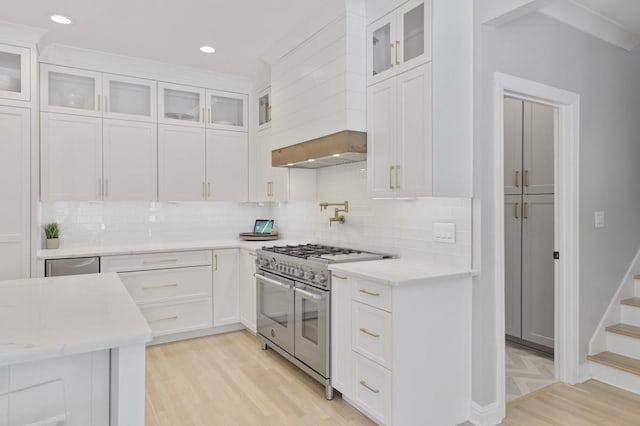 kitchen featuring double oven range, light stone countertops, light hardwood / wood-style flooring, and white cabinets