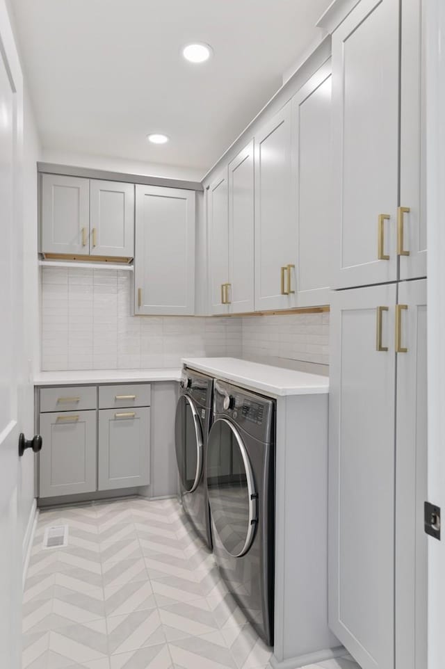 washroom featuring cabinets, light tile patterned floors, and washer and clothes dryer