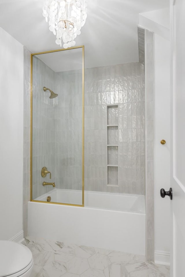 bathroom with an inviting chandelier, tiled shower / bath, and toilet