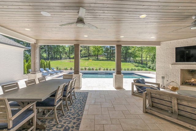 view of patio featuring an outdoor brick fireplace and ceiling fan