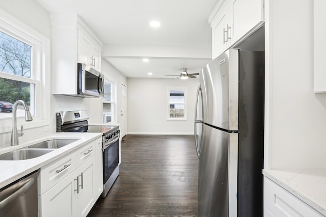 kitchen with sink, white cabinets, stainless steel appliances, light stone countertops, and dark wood-type flooring