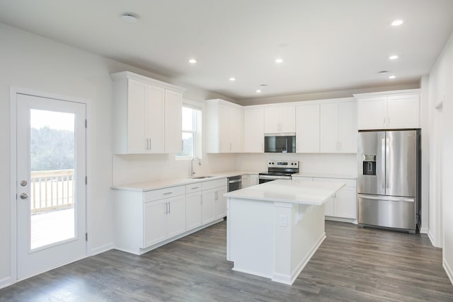 kitchen with sink, stainless steel appliances, dark hardwood / wood-style floors, a center island, and white cabinets