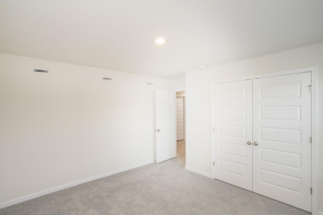 unfurnished bedroom with light colored carpet and a closet