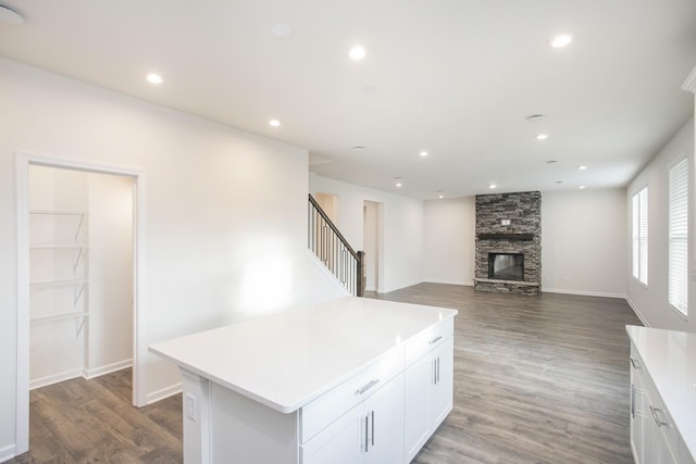 kitchen featuring white cabinetry, wood-type flooring, a fireplace, and a center island