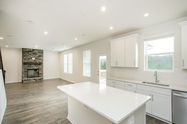 kitchen with sink, white cabinetry, dishwasher, a kitchen island, and backsplash