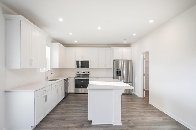 kitchen featuring appliances with stainless steel finishes, dark hardwood / wood-style flooring, a kitchen island, and white cabinets