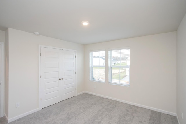 unfurnished bedroom with light colored carpet and a closet