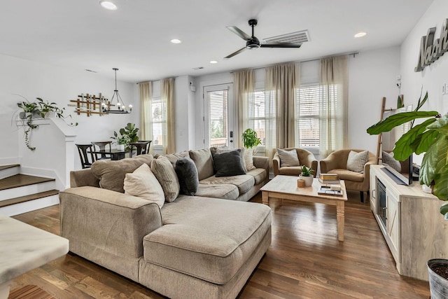 living room featuring dark hardwood / wood-style flooring and ceiling fan with notable chandelier