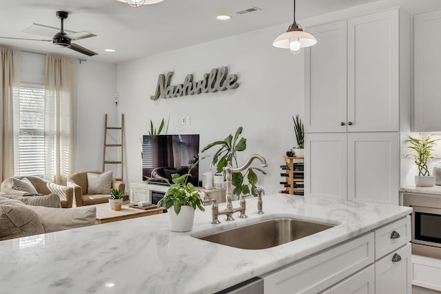 kitchen featuring decorative light fixtures, white cabinetry, sink, ceiling fan, and light stone countertops