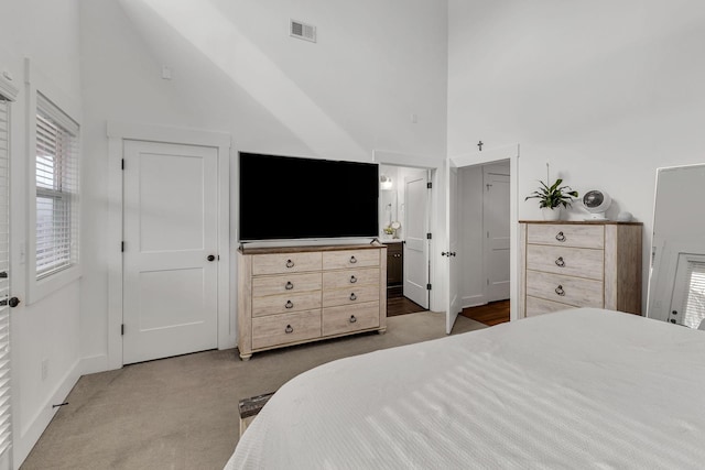 bedroom with ensuite bath, high vaulted ceiling, and carpet floors