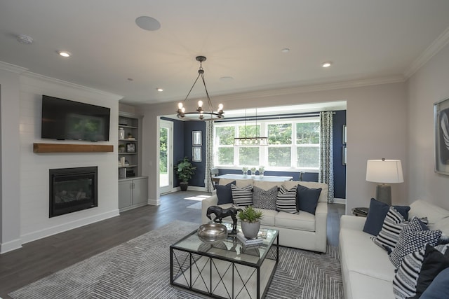 living room with dark wood-type flooring, ornamental molding, a fireplace, and a chandelier