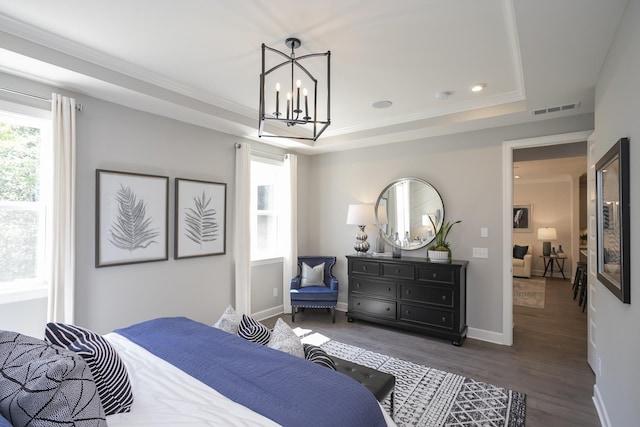 bedroom with a raised ceiling, ornamental molding, an inviting chandelier, and dark hardwood / wood-style flooring