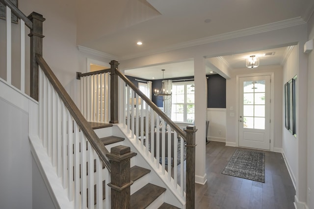 foyer entrance with an inviting chandelier, ornamental molding, and dark hardwood / wood-style floors