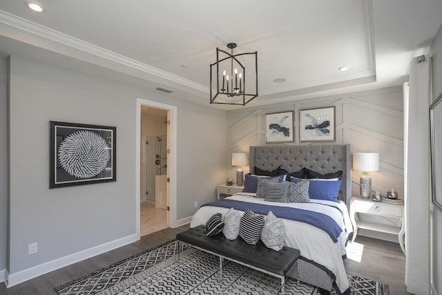 bedroom with ornamental molding, dark wood-type flooring, a notable chandelier, and a tray ceiling