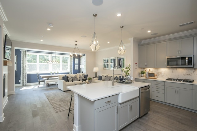 kitchen featuring appliances with stainless steel finishes, gray cabinets, and a kitchen island with sink