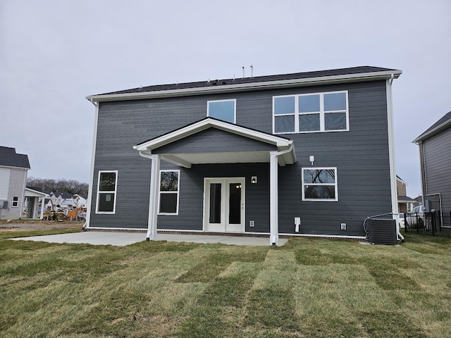 rear view of property featuring a patio, a yard, and central AC