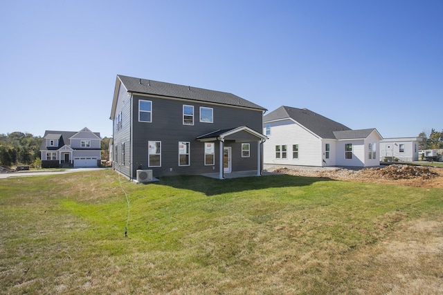 rear view of property with a garage, a lawn, and ac unit