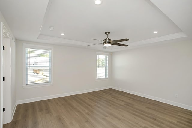 empty room with crown molding, wood-type flooring, and a raised ceiling