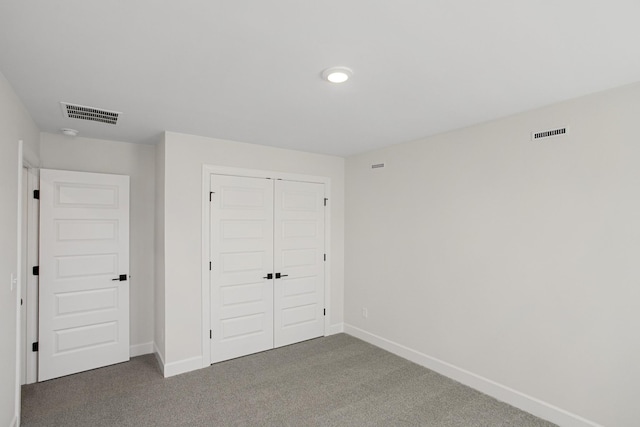 unfurnished bedroom with dark carpet and a closet