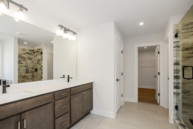 bathroom featuring a shower with door and vanity