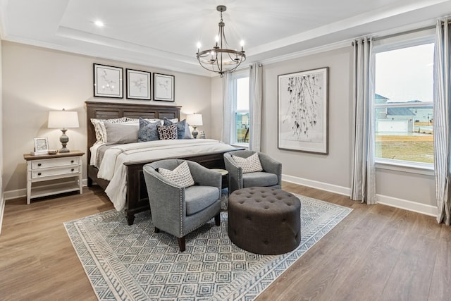 bedroom featuring a raised ceiling, hardwood / wood-style floors, and multiple windows