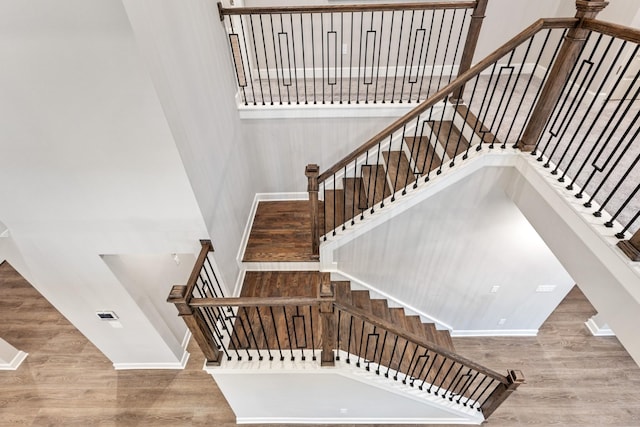 stairway featuring a towering ceiling and hardwood / wood-style floors