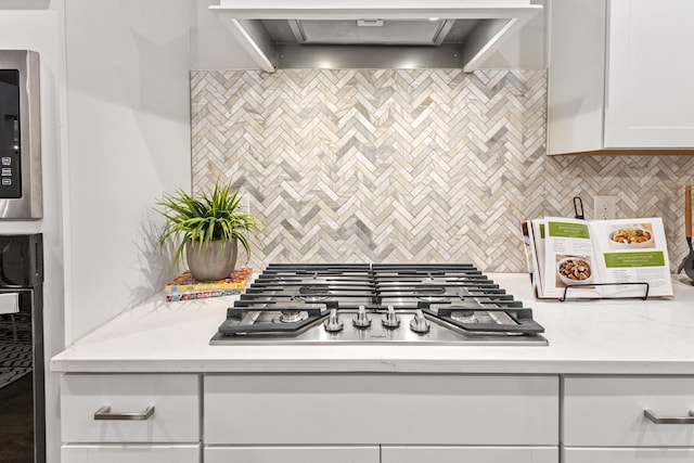 kitchen with white cabinetry, stainless steel gas stovetop, tasteful backsplash, and wall chimney exhaust hood