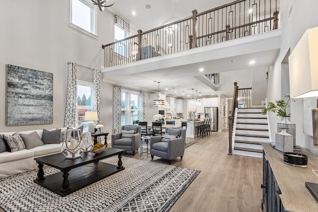 living room featuring a notable chandelier, a towering ceiling, and light wood-type flooring