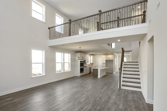 unfurnished living room featuring a towering ceiling and dark hardwood / wood-style flooring