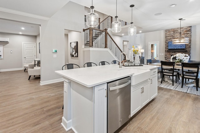 kitchen featuring decorative light fixtures, white cabinetry, dishwasher, sink, and an island with sink