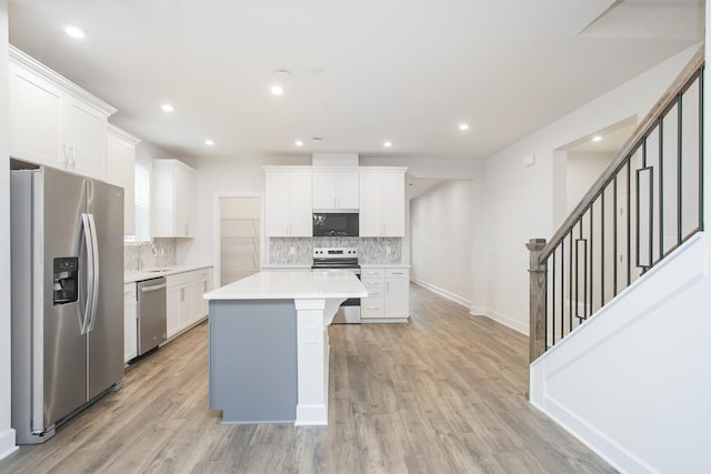 kitchen featuring a kitchen island, white cabinetry, sink, light hardwood / wood-style floors, and stainless steel appliances