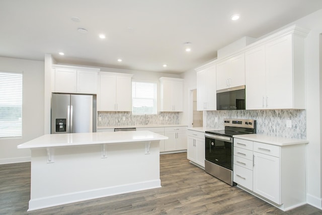 kitchen with stainless steel appliances, a center island, decorative backsplash, and white cabinets