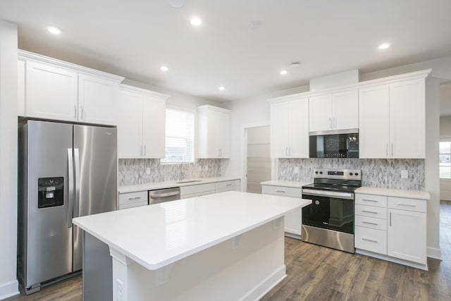 kitchen with white cabinetry, stainless steel appliances, dark hardwood / wood-style floors, and a kitchen island