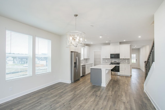 kitchen featuring appliances with stainless steel finishes, hanging light fixtures, a center island, tasteful backsplash, and white cabinets