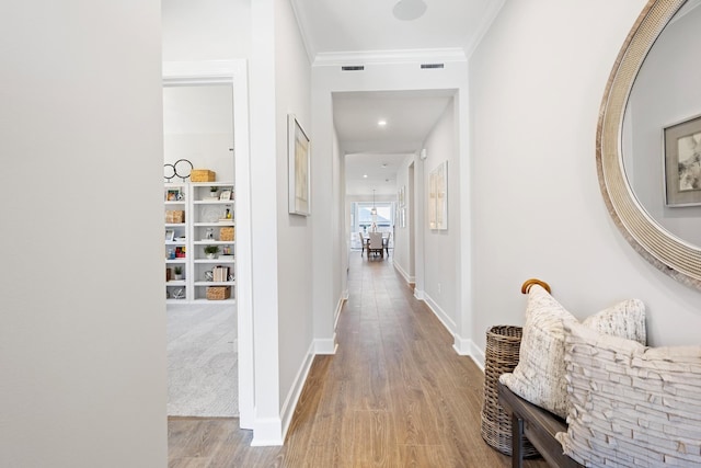 hallway with ornamental molding and light hardwood / wood-style floors