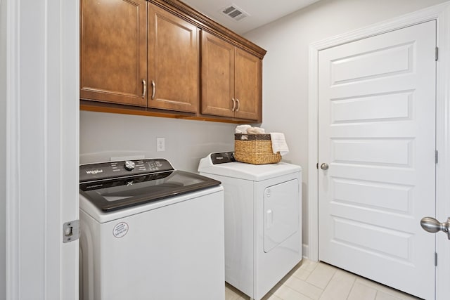 washroom featuring independent washer and dryer, cabinets, and light tile patterned flooring