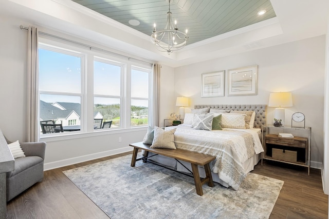 bedroom featuring a raised ceiling, ornamental molding, dark wood-type flooring, and a notable chandelier