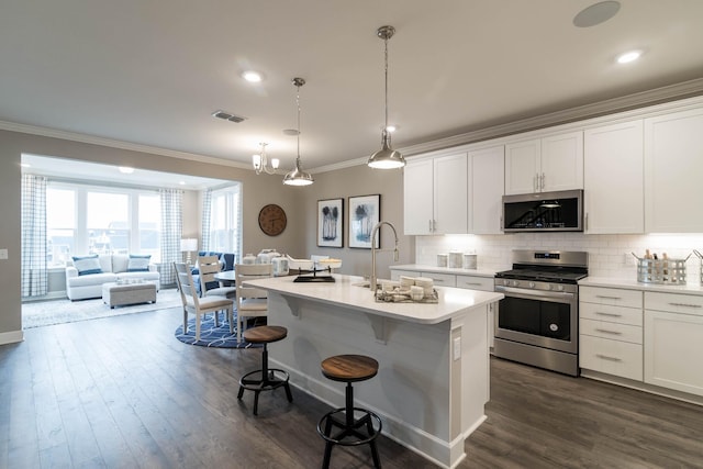 kitchen with appliances with stainless steel finishes, sink, a kitchen island with sink, and white cabinets