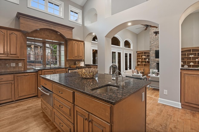 kitchen with ceiling fan, light hardwood / wood-style floors, a kitchen island with sink, and sink