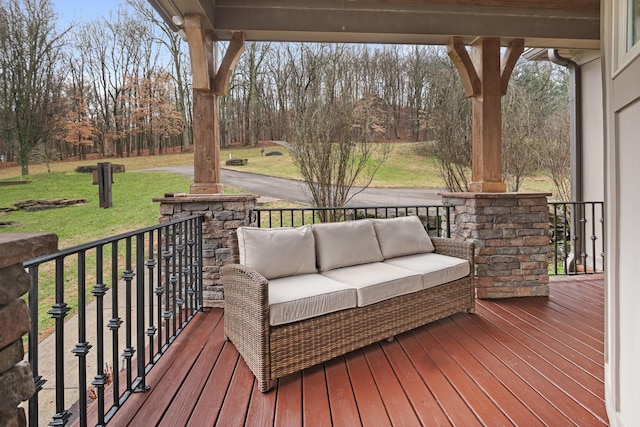 wooden terrace featuring a lawn and covered porch