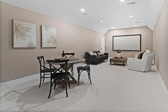 carpeted dining space featuring vaulted ceiling